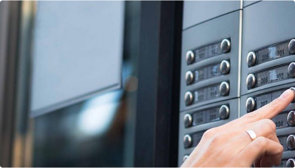 Hand pressing a button on a distribution center intercom.