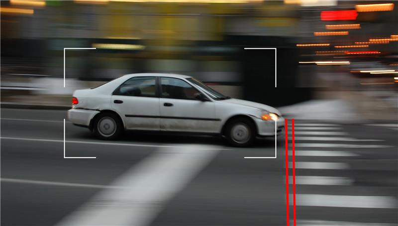 White car driving across a crosswalk with video framing.